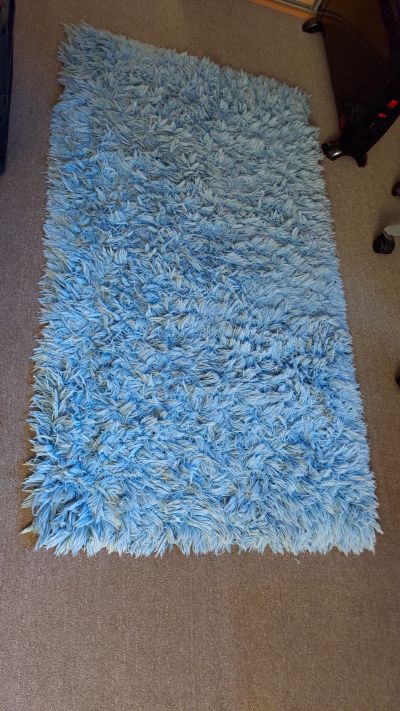 Modrý chlupatý koberec, předložka před postel