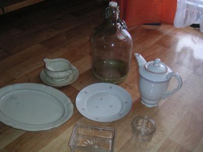 Skleněný demižon a různé porcelánové/skleněné nádobí.