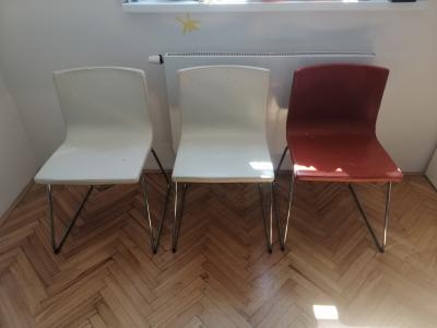Tři židlě (dvě bílé a jedna červená).