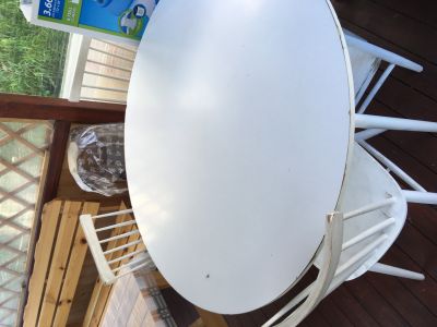 Kulatý bílý stůl a čtyři židle.